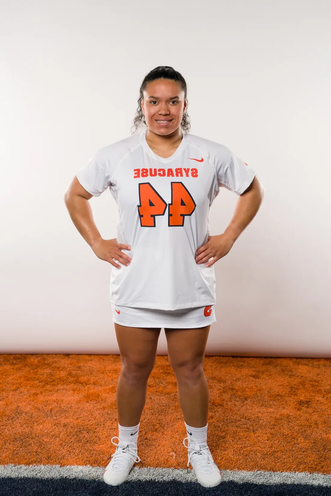 Person standing with hands on hips in sports uniform.